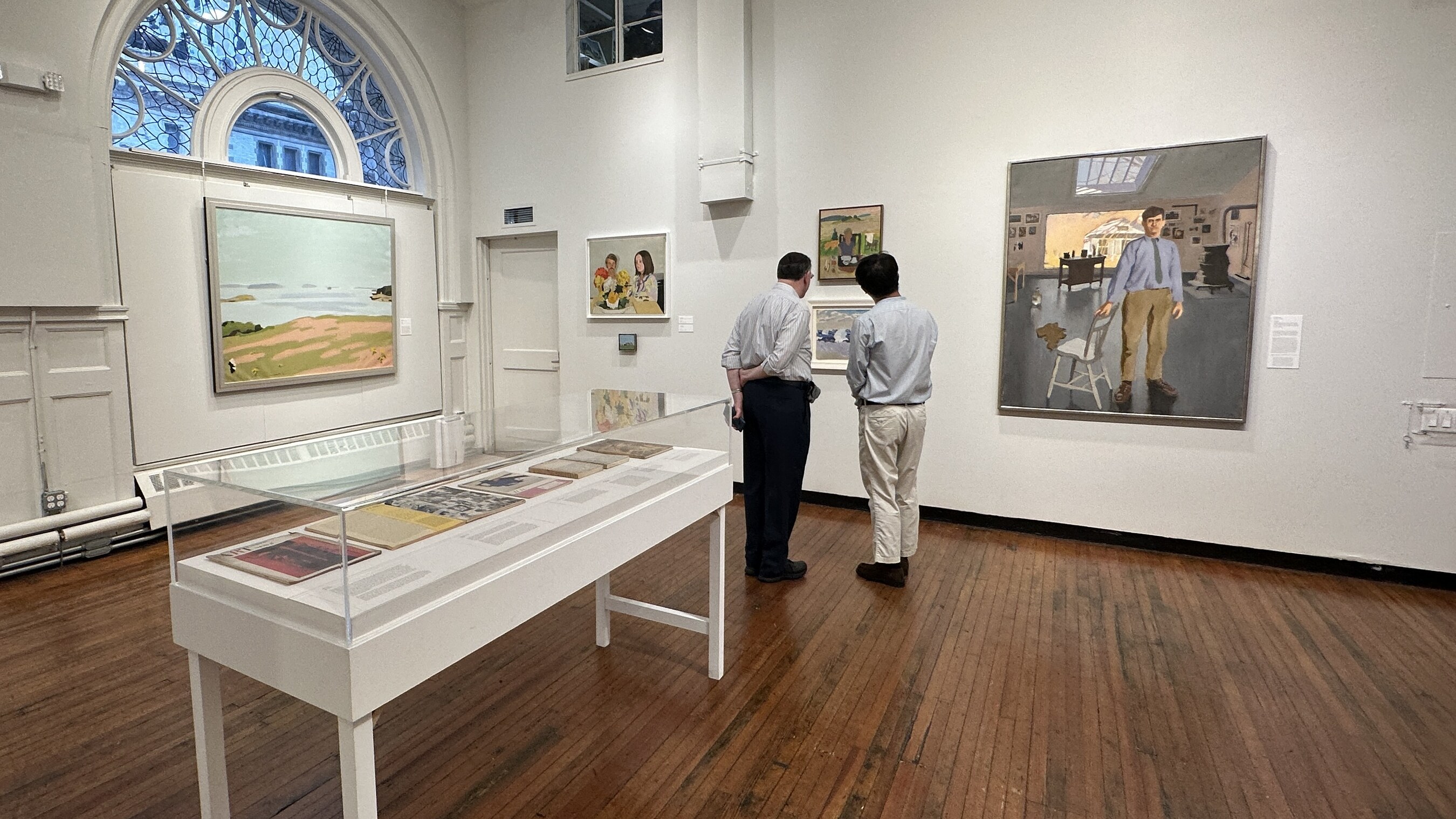 Two people looking closely at artwork in a small gallery